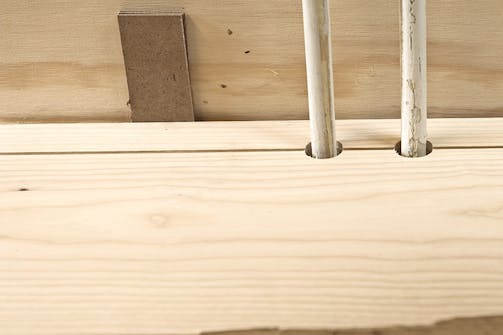 Samling mellem to langsgående gulvbrædder: Det yderste bræt lægges på plads med afstandskiler ind mod væggen, og det næste bræt bankes på plads med et slagjern Samling mellem to langsgående gulvbrædder: Det yderste bræt lægges på plads med afstandskiler ind mod væggen, og det næste bræt bankes på plads med et slagjern